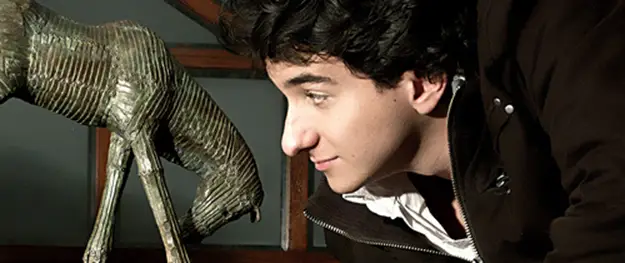 Joaquín Restrepo observa atentamente una versión en bronce de su escultura Miserere, una figura ecuestre en gesto de reverencia.